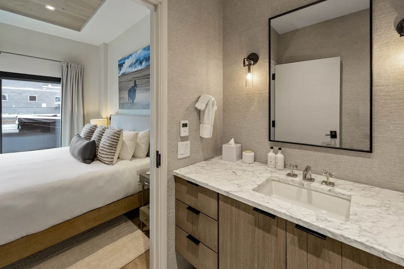 A bedroom and adjoining bathroom are visible, with a bed and a sink vanity.