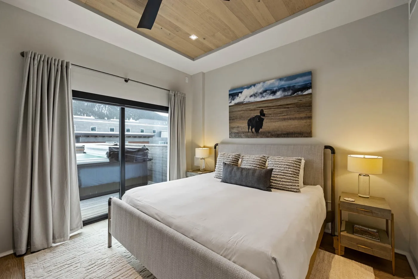 A bedroom with a neatly made bed, bedside tables, and sliding glass doors.
