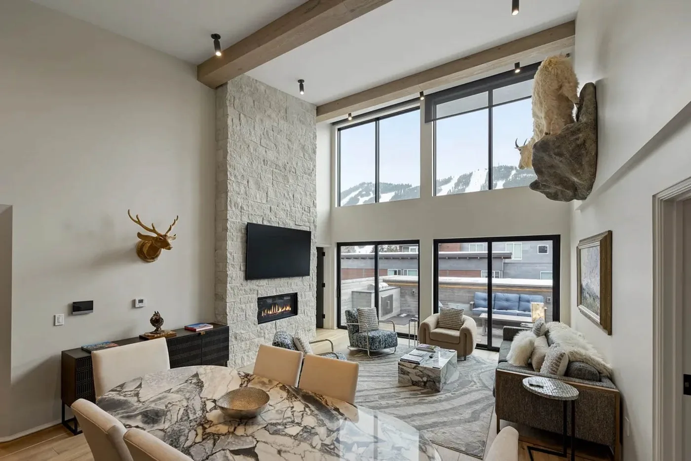 A bright living room with a stone fireplace and large windows overlooking the outdoors.