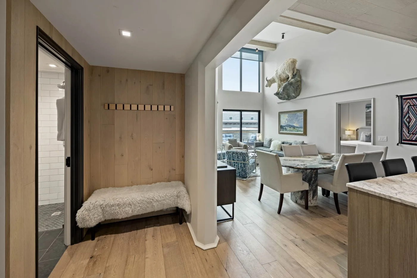 A wood-paneled entryway opens onto a bright dining and living area.