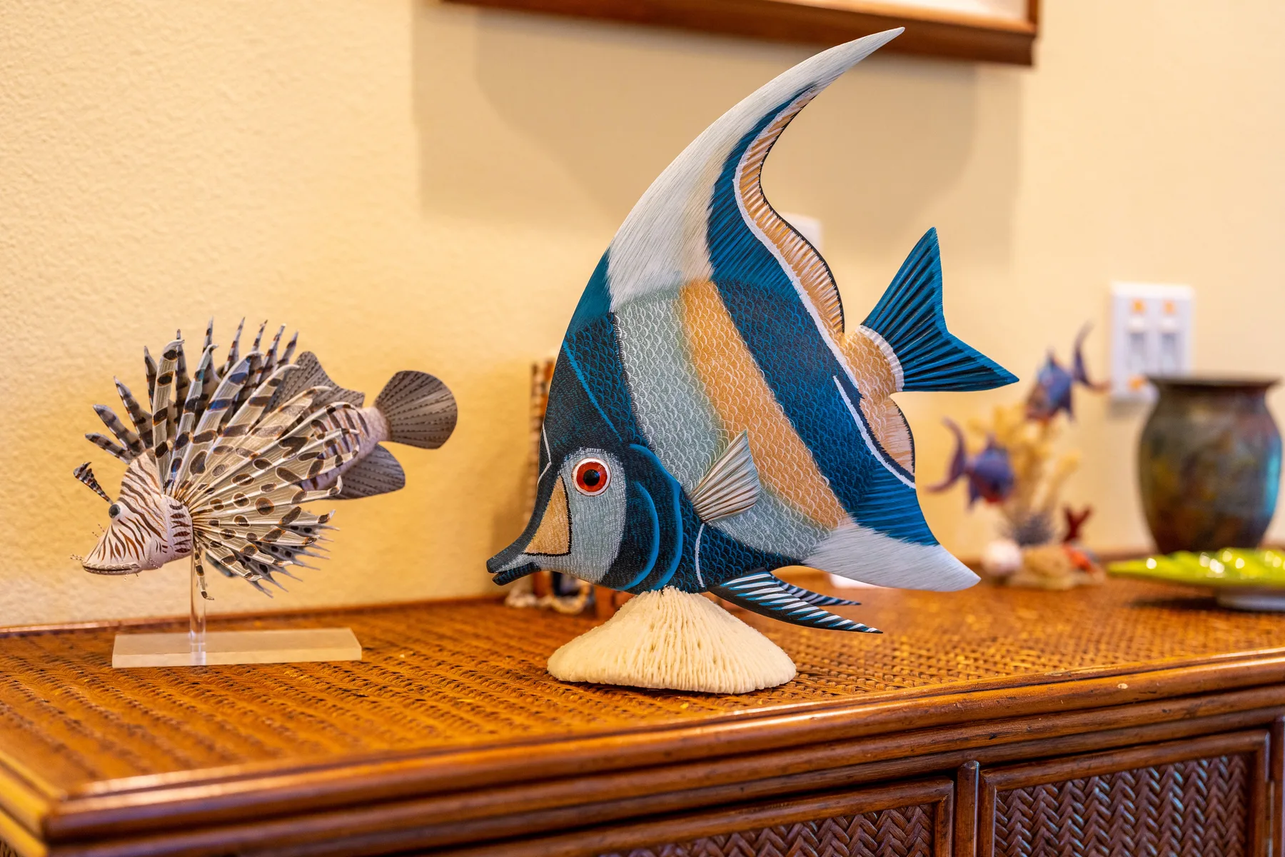 Decorative fish sculptures sit on a wooden console against a cream wall.