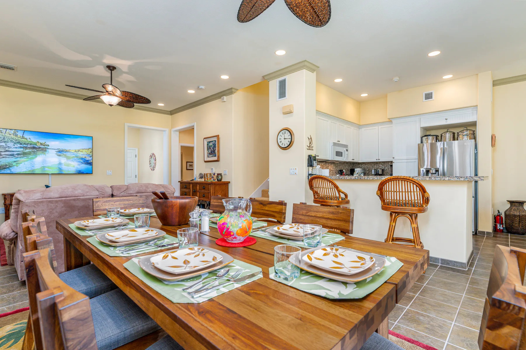 A dining area with a set table, seating, and an open kitchen in the background.