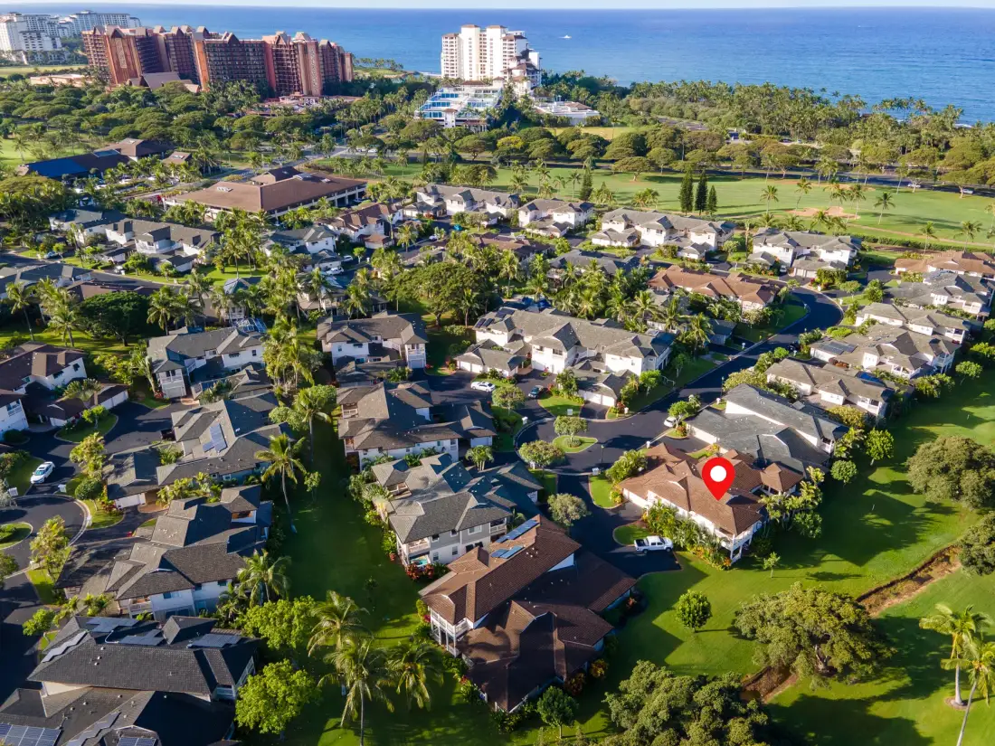 An aerial view of a residential neighborhood with the ocean in the distance.