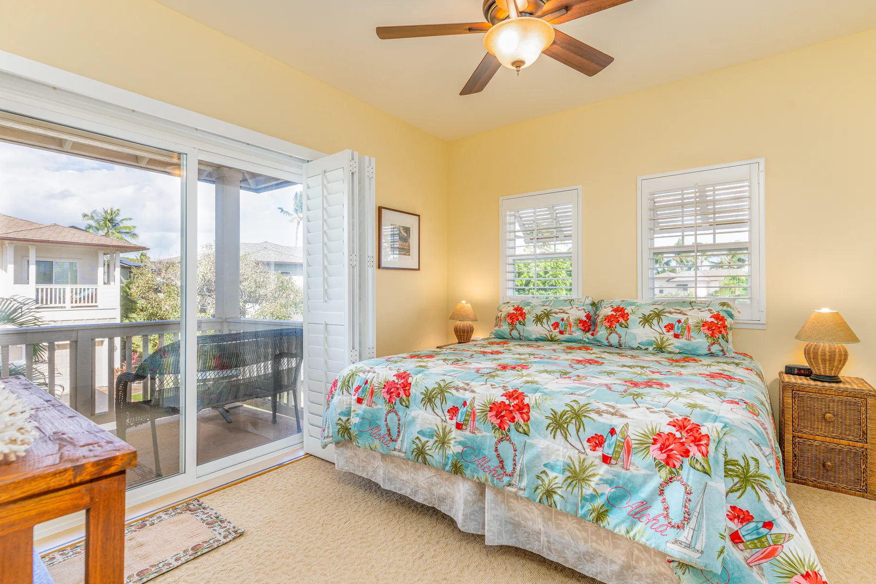 A bedroom with a floral bedspread and a sliding glass door opening to a balcony.