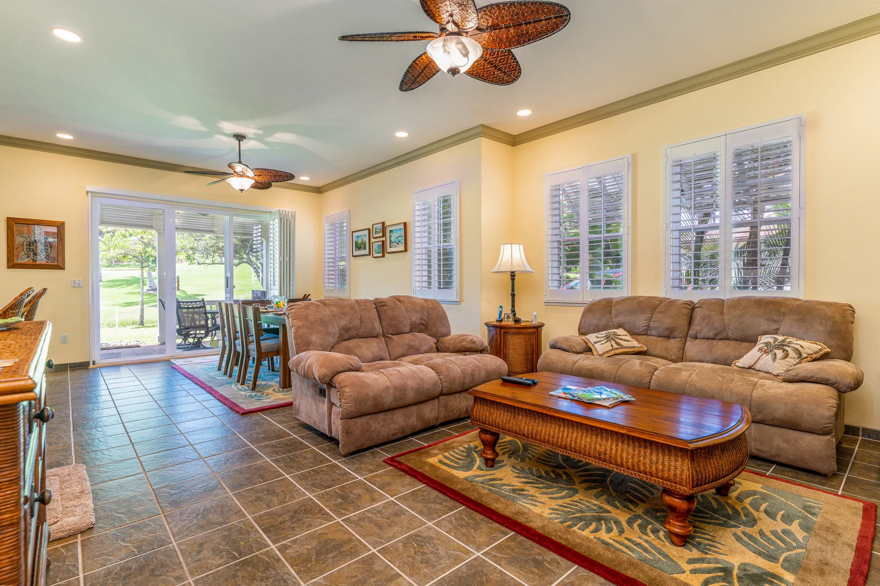 A living room with seating, a coffee table, and windows overlooking greenery.