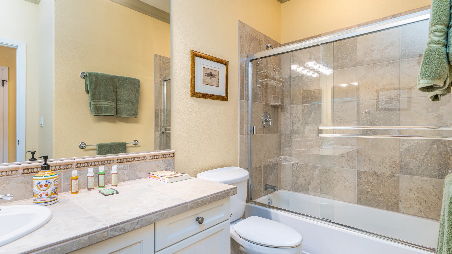 A bathroom with a bathtub, glass shower screen, and vanity.
