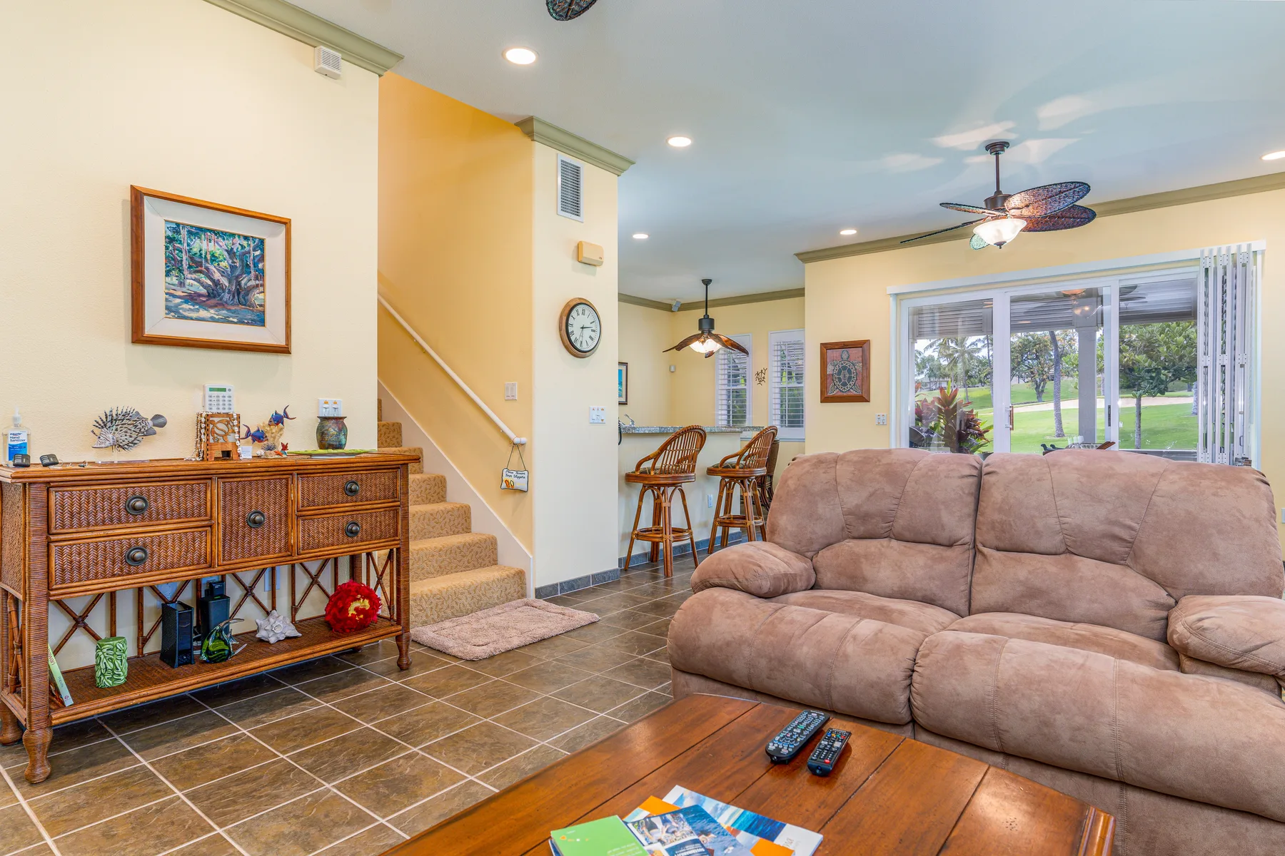 A living room with a sofa, coffee table, dining area, and large windows.