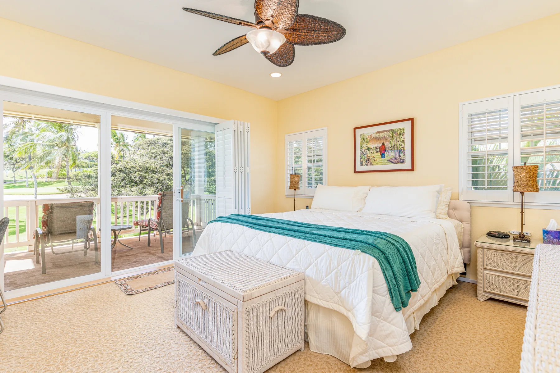 A bright bedroom with a white bed and sliding glass doors opening to a patio.