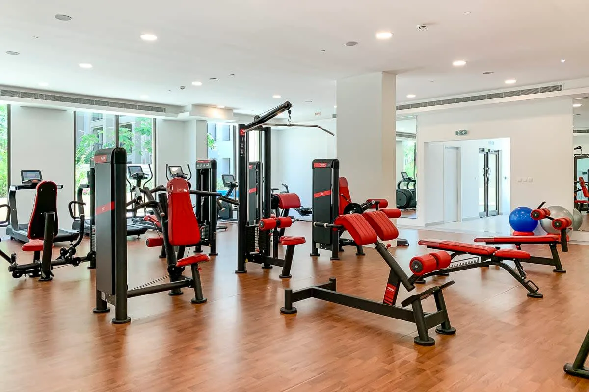 Un gimnasio con máquinas de ejercicio, pesas y espacio libre.