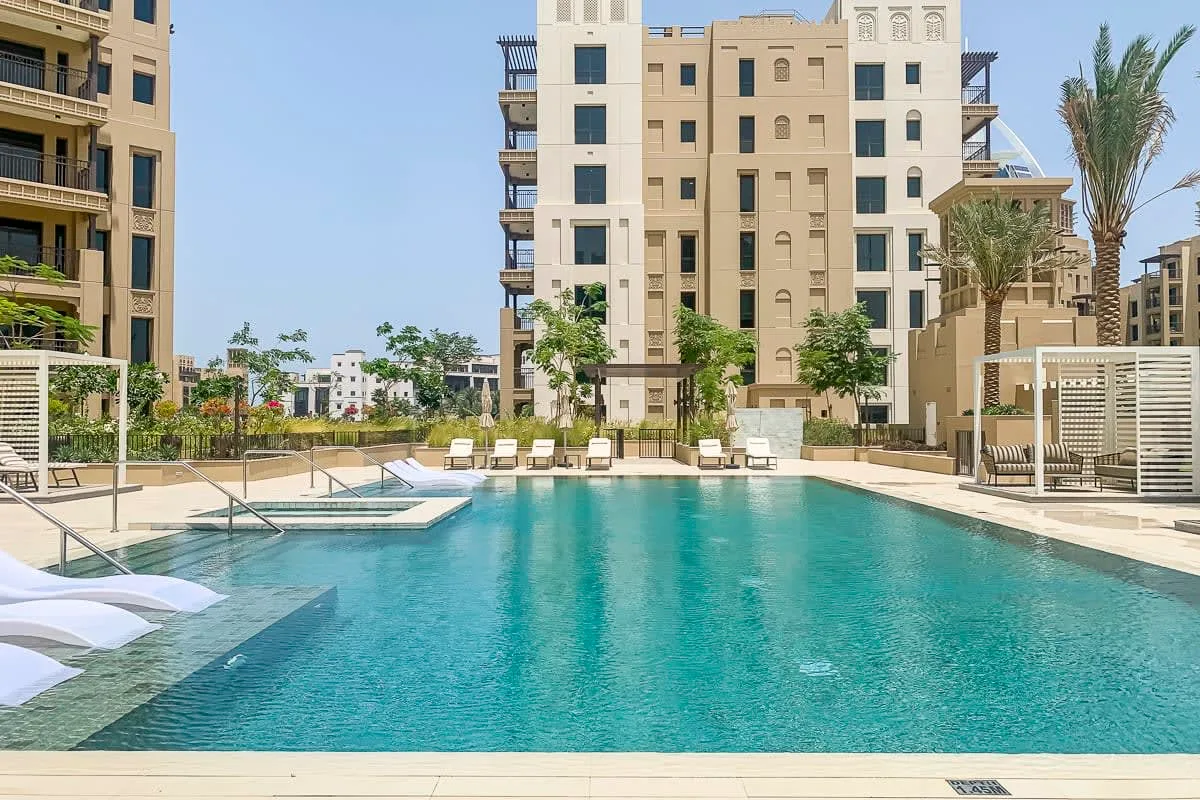 Una piscina al aire libre está rodeada de edificios de apartamentos y jardines.