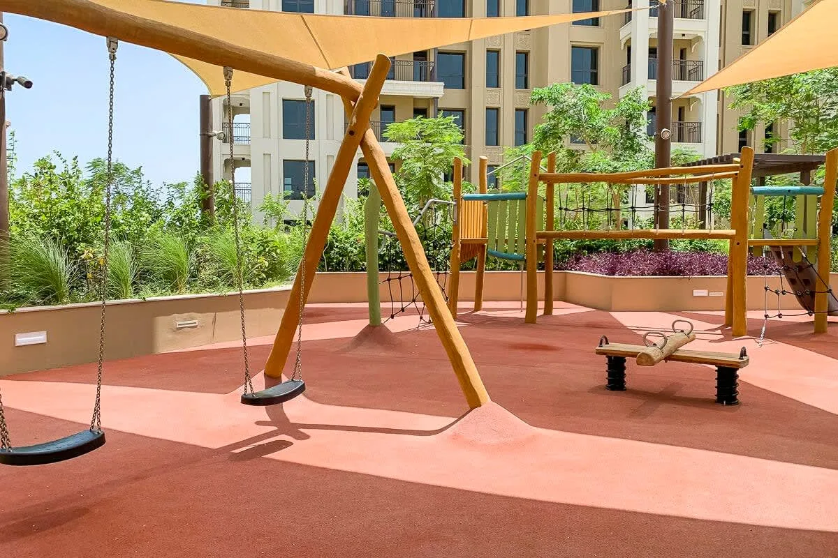 Un área de juegos al aire libre con columpios y un pequeño balancín bajo toldos.