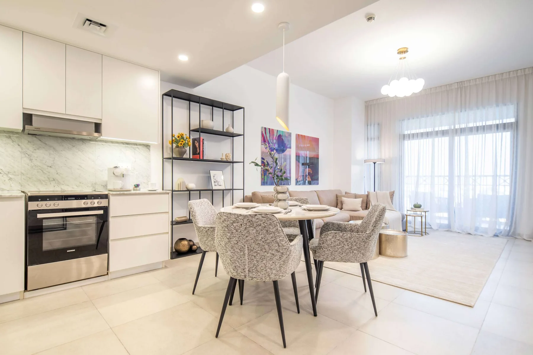 Cocina y comedor diáfanos y luminosos, con una mesa junto a grandes ventanas.