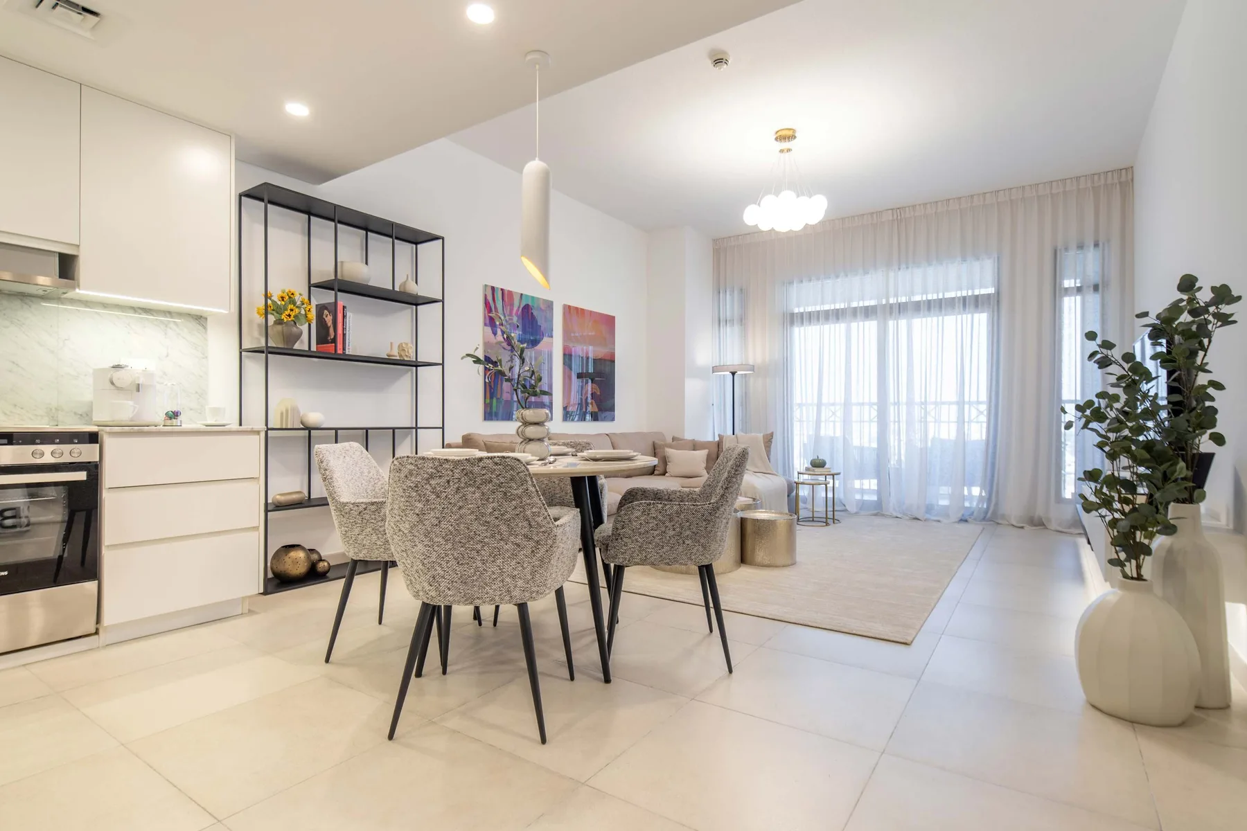 Una luminosa cocina-comedor abierta con una mesa junto a grandes ventanas con cortinas.