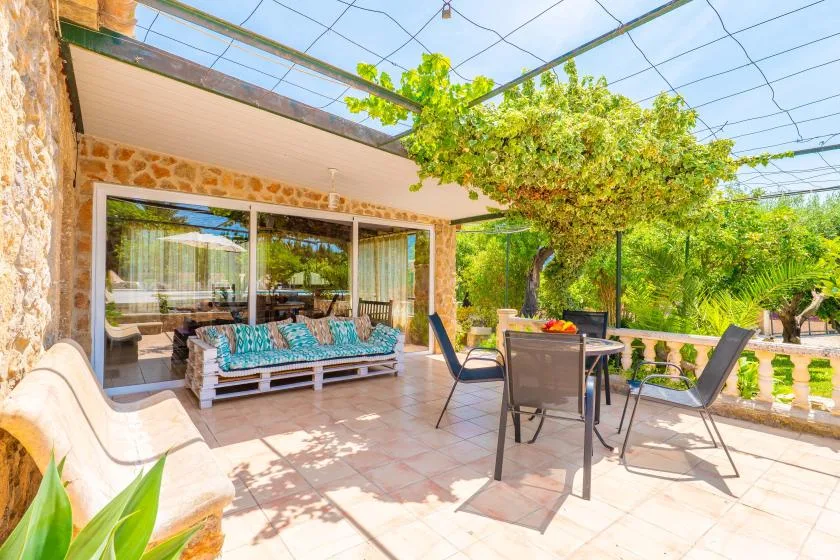 A covered outdoor patio with a dining table, seating, and garden views.
