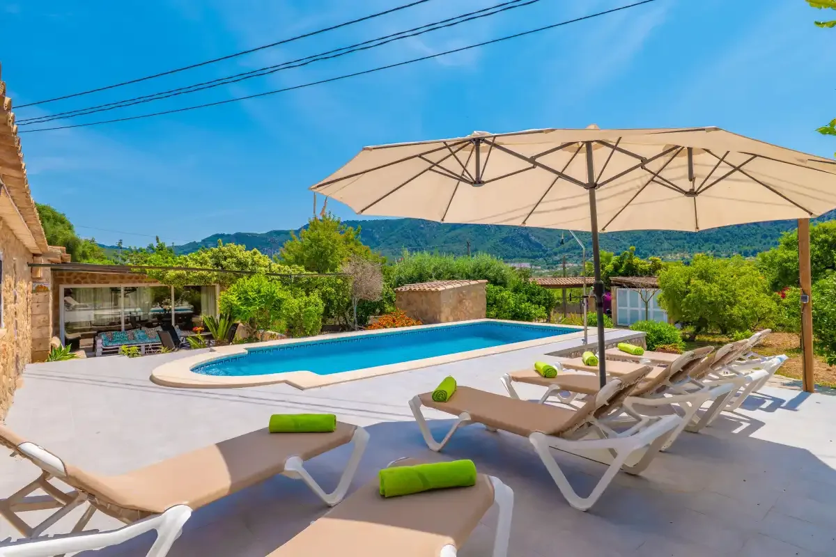 A sunny pool patio with lounge seating and a large shade umbrella.