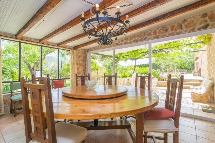 A dining area with wooden tables beside large windows overlooking a garden.