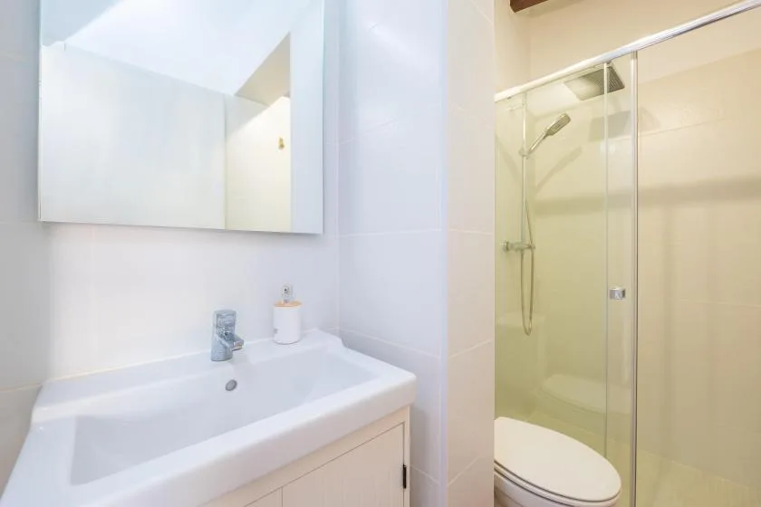 A bathroom with a sink and a glass-enclosed shower.