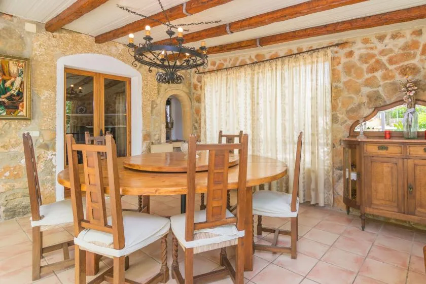 A rustic dining room with a wooden table, chairs, and stone walls.