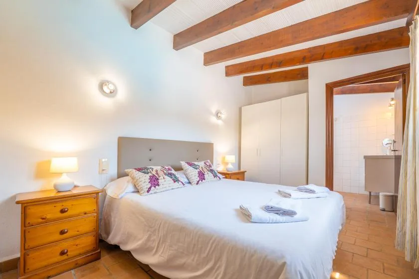 A bedroom with a double bed, bedside tables, and exposed wooden ceiling beams.