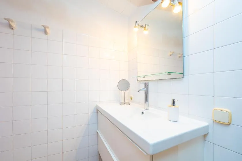 A tiled bathroom with a white sink and wall mirror.