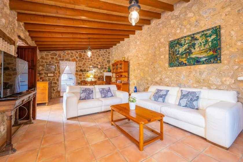 A stone-walled living room with white seating and a wooden coffee table.