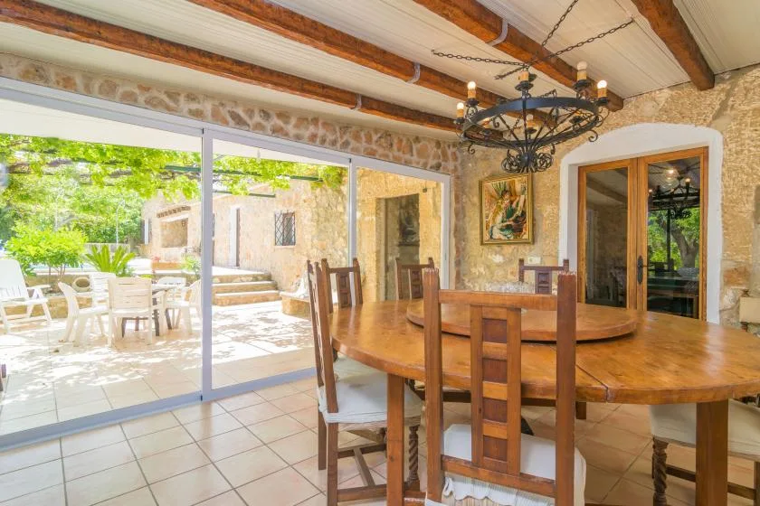 A dining area with a wooden table beside large glass doors opening to a patio.