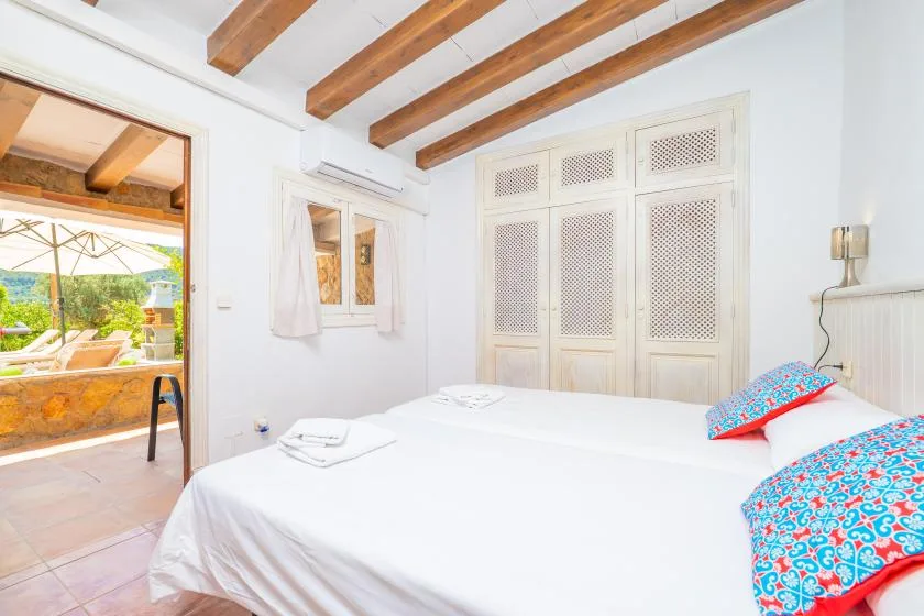 A bright bedroom with white bedding and wooden ceiling beams.