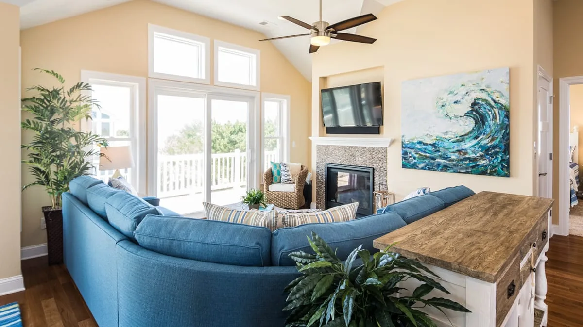 Una sala luminosa con asientos azules, una chimenea y ventanas grandes.