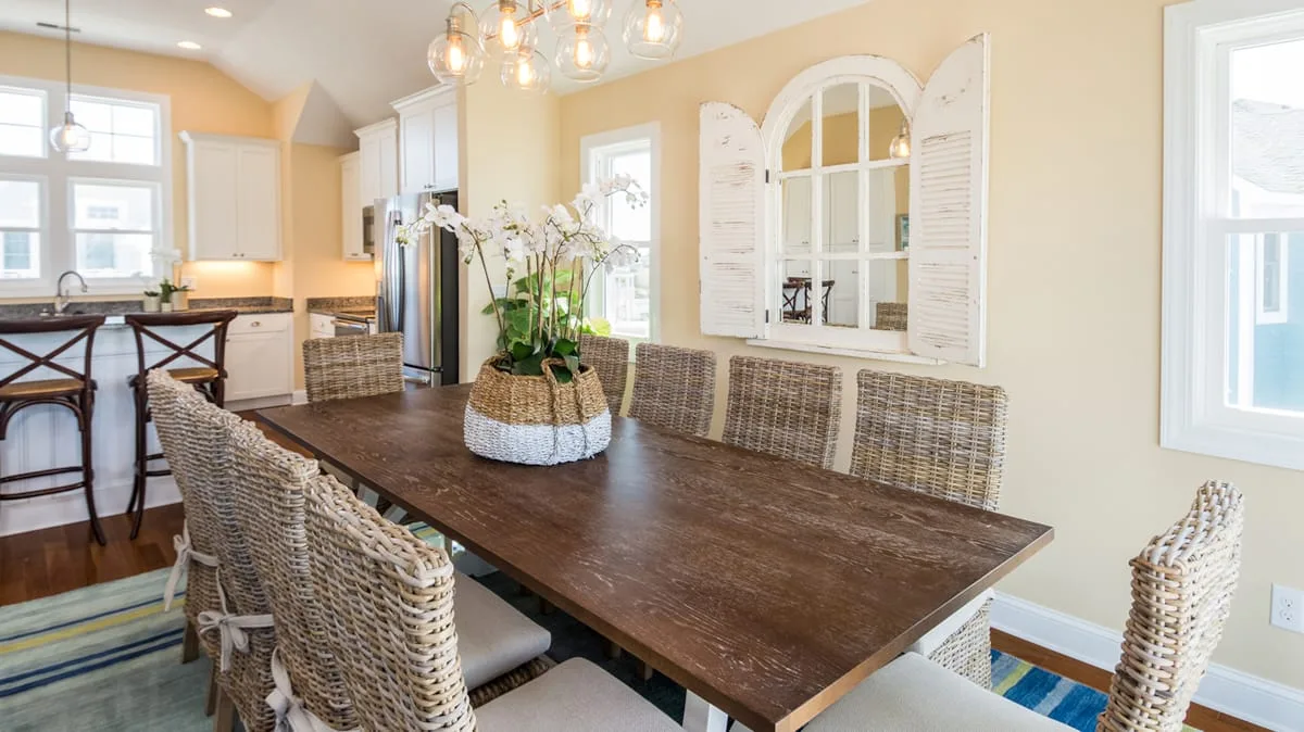 Un comedor con una mesa larga de madera y asientos tejidos.