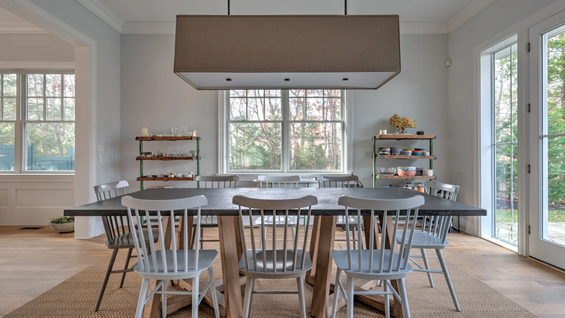 Un comedor luminoso con una mesa larga y sillas junto a grandes ventanas.