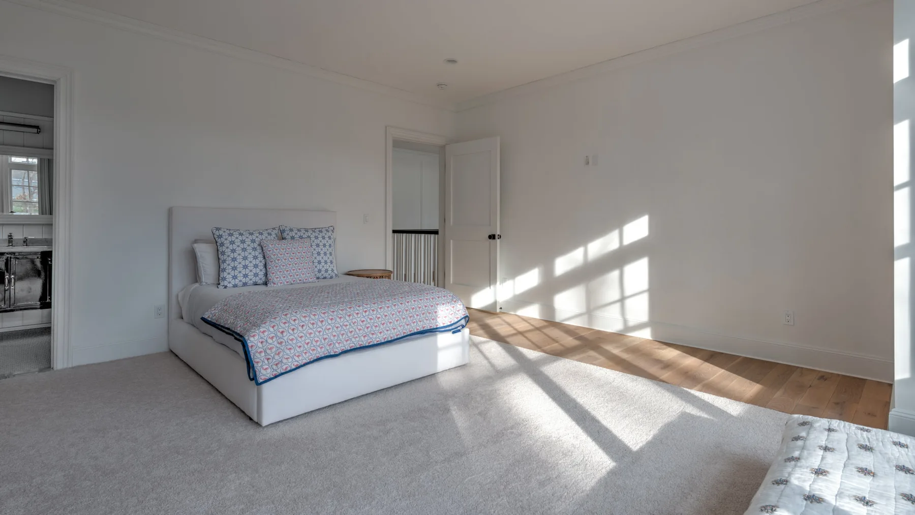 Un dormitorio luminoso con una cama y luz del sol sobre el suelo.