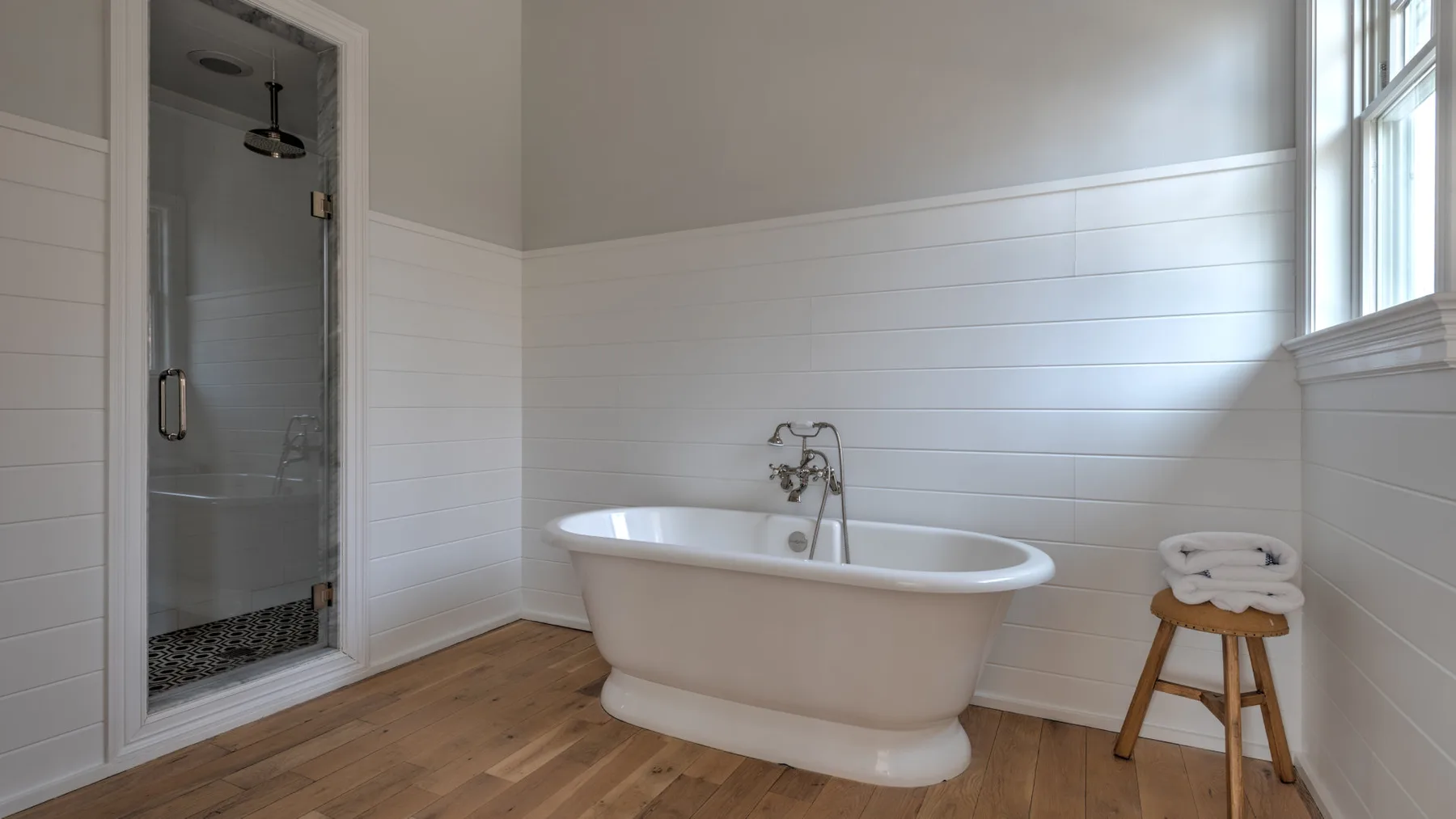 Un baño luminoso con una bañera exenta junto a una ducha.