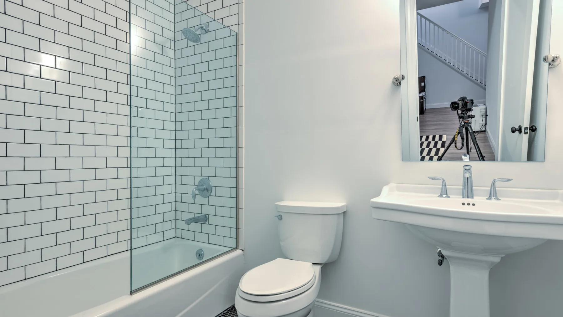 Un baño luminoso con bañera revestida de azulejos, inodoro y lavabo con pedestal.