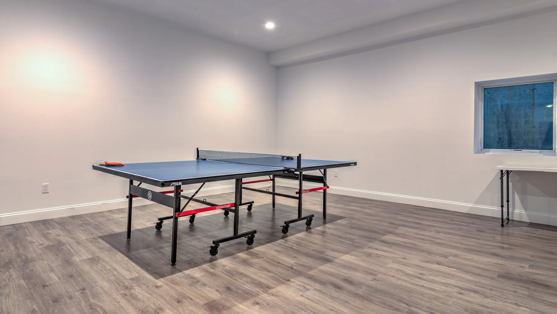 Una mesa de ping-pong está en una amplia sala de recreación interior.