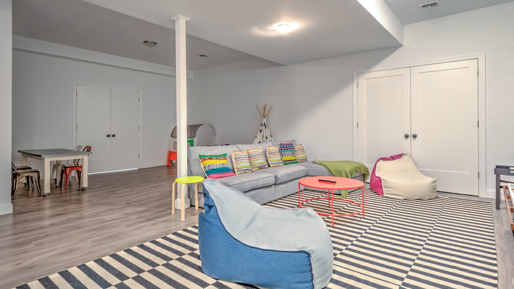 Una sala de estar luminosa con un sofá gris y una alfombra a rayas.