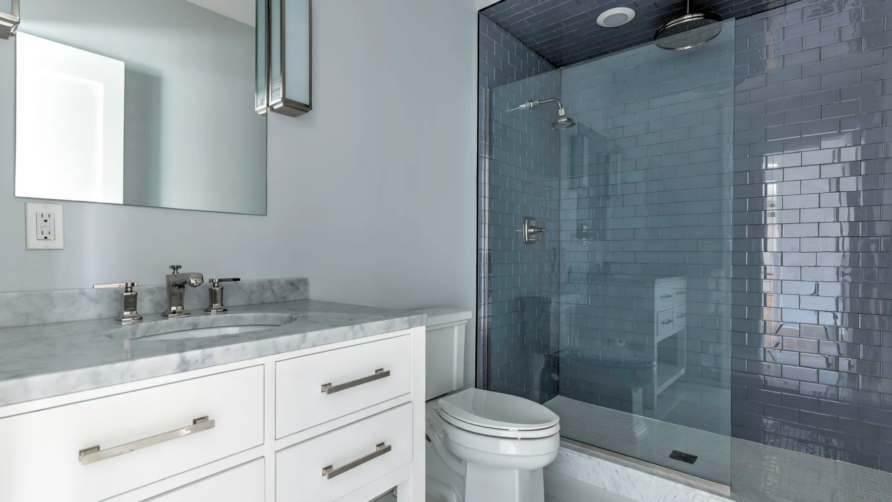 Un baño moderno con un tocador largo y una ducha de vidrio.