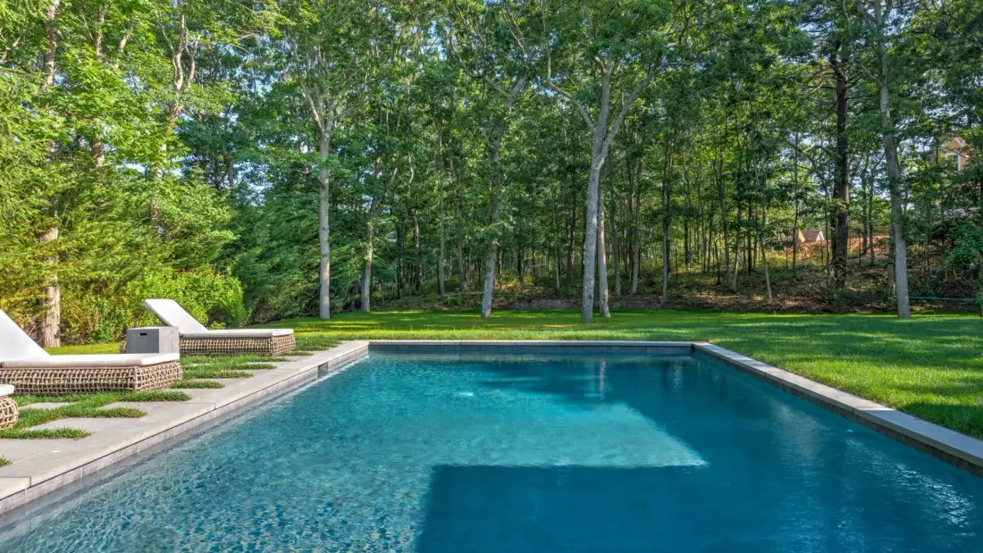 Una piscina al aire libre está junto a una zona arbolada.