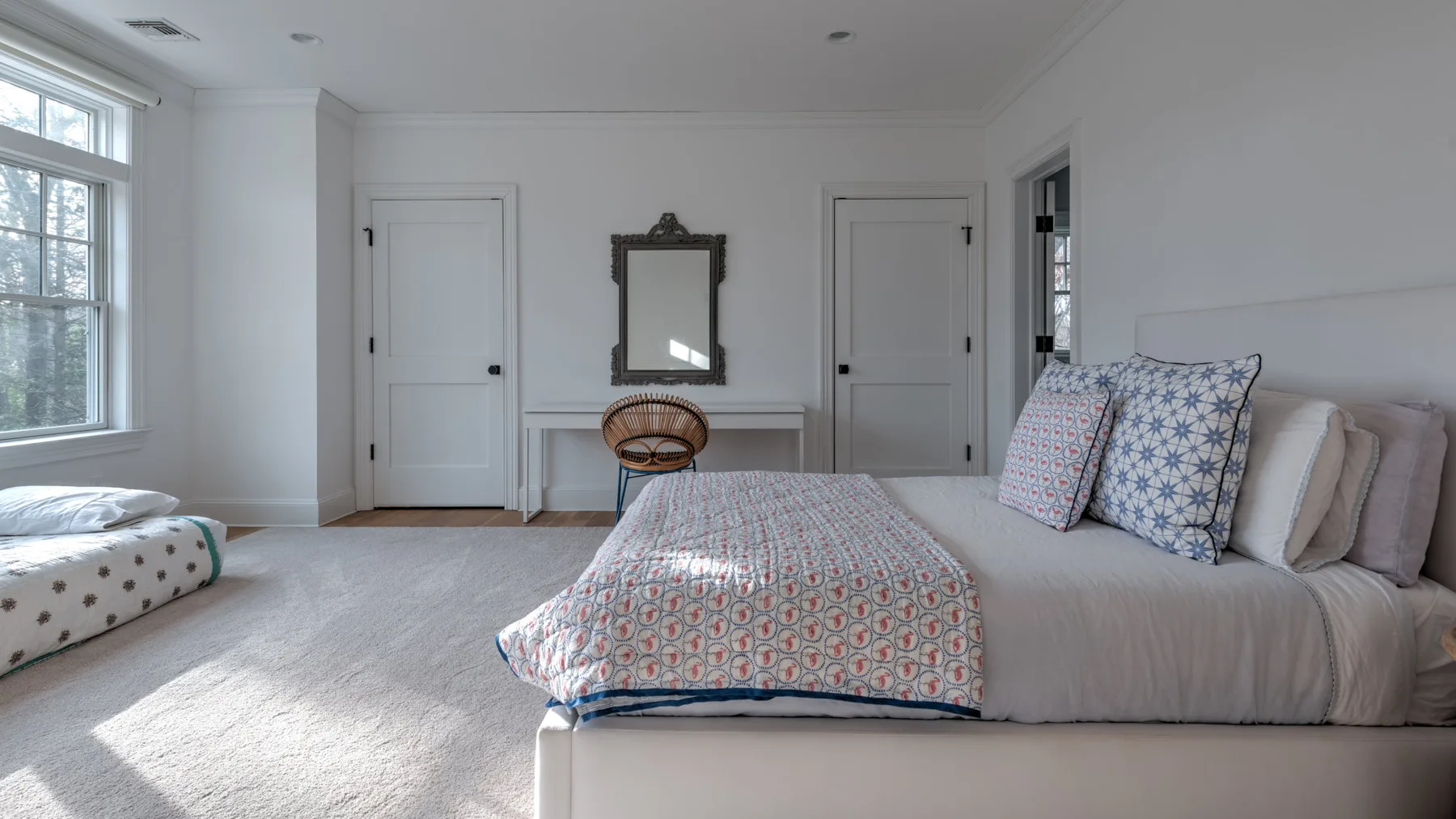 Un dormitorio luminoso con una cama grande y una ventana con vista a los árboles.
