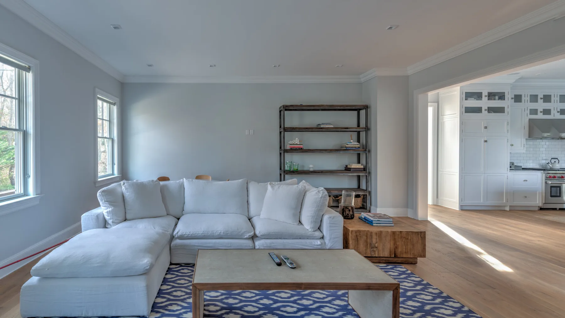 Una sala luminosa tiene un sofá seccional, una mesa de centro y vista abierta a la cocina.