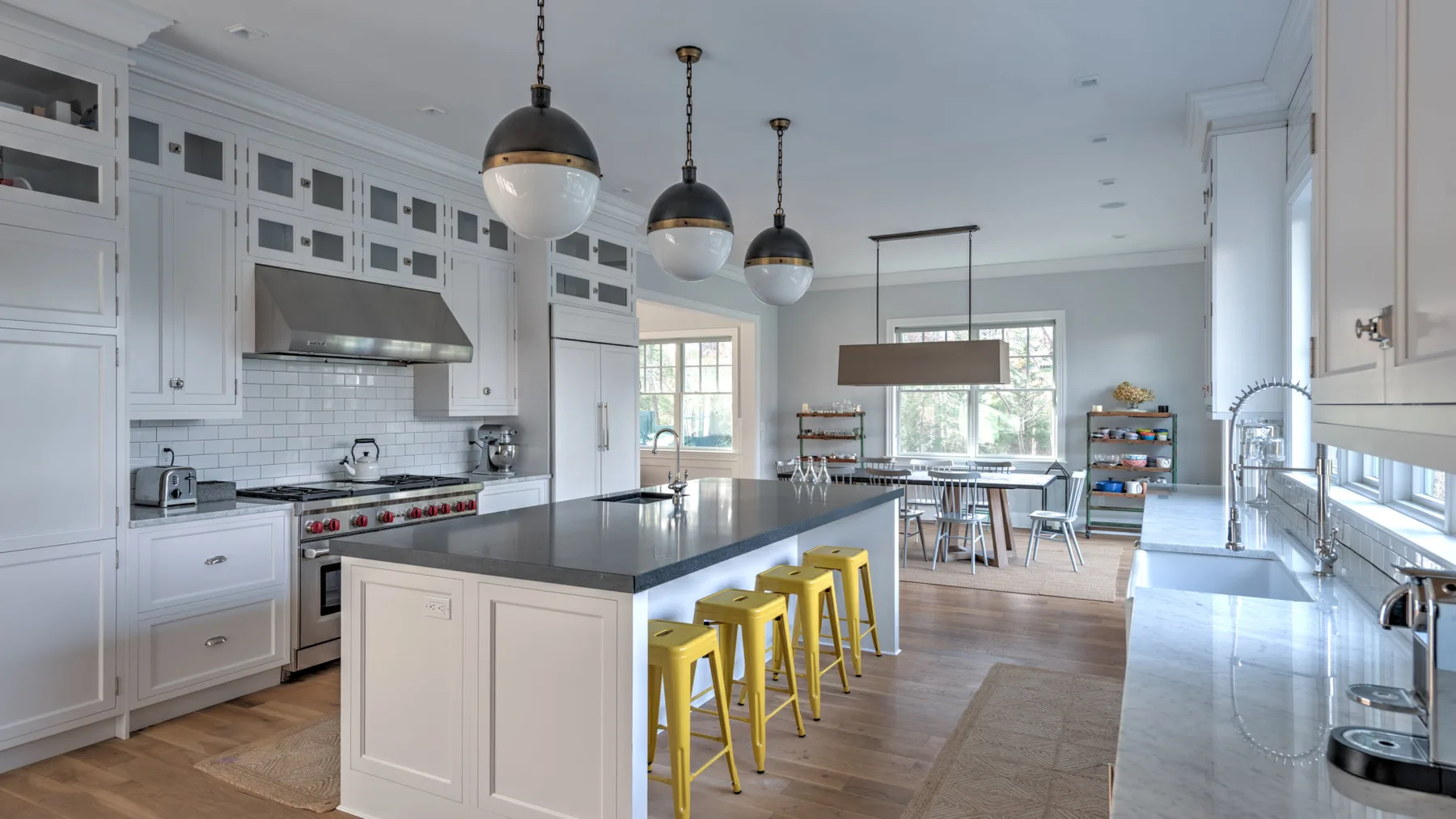 Una cocina luminosa con una isla central y taburetes amarillos.