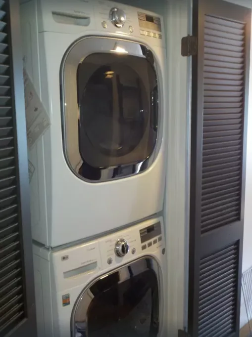 A stacked washer and dryer are set between louvered doors.