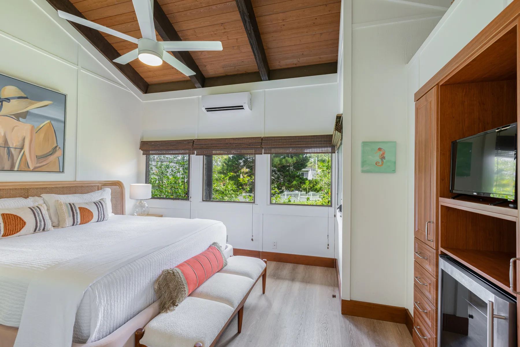 A bright bedroom with a large bed beneath a wood-paneled ceiling.