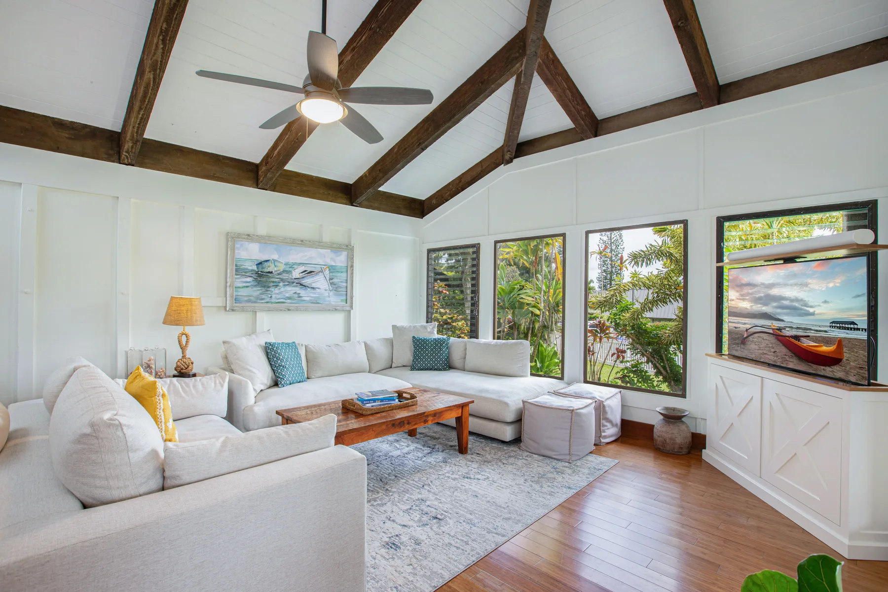 A bright living room with sectional seating, a coffee table, and large windows.
