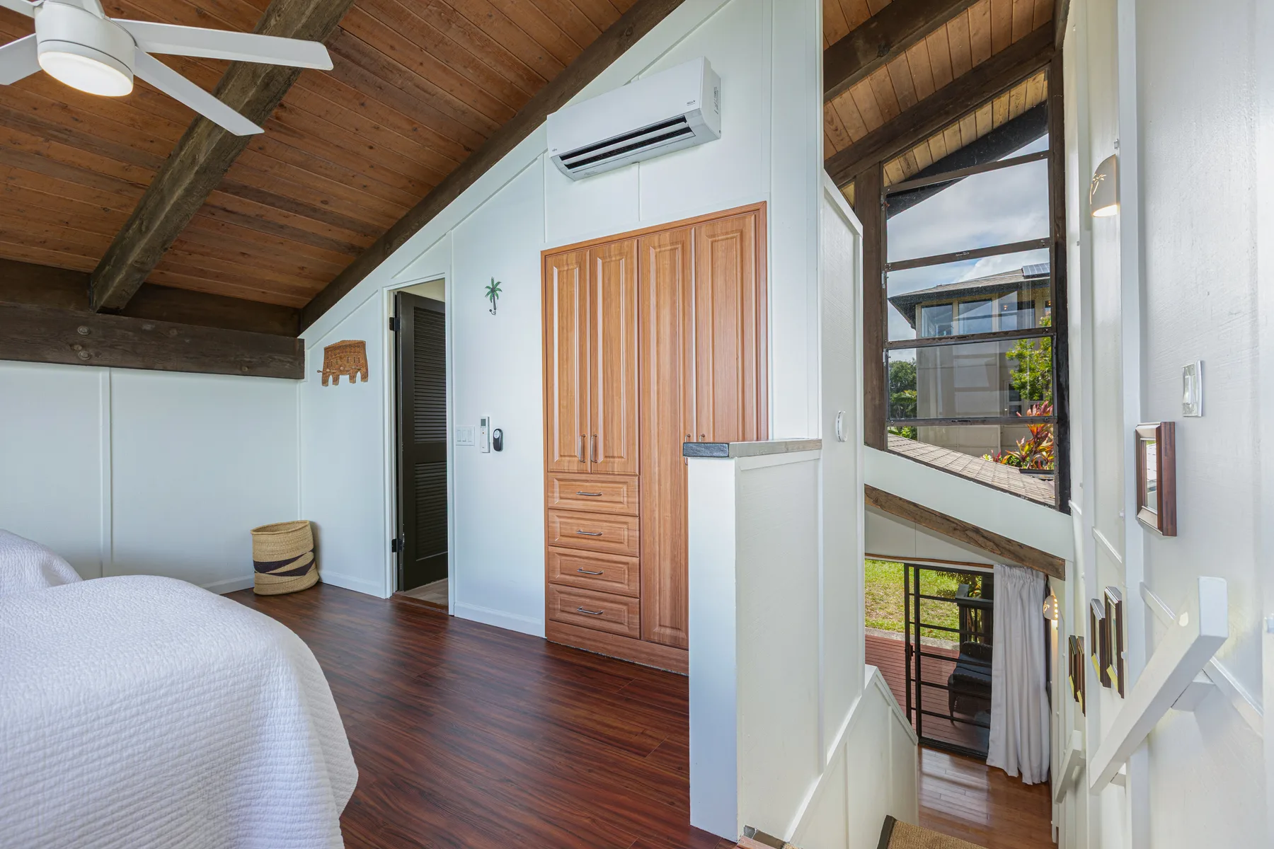 A bedroom with a wooden ceiling, a bed, and a tall wooden wardrobe.