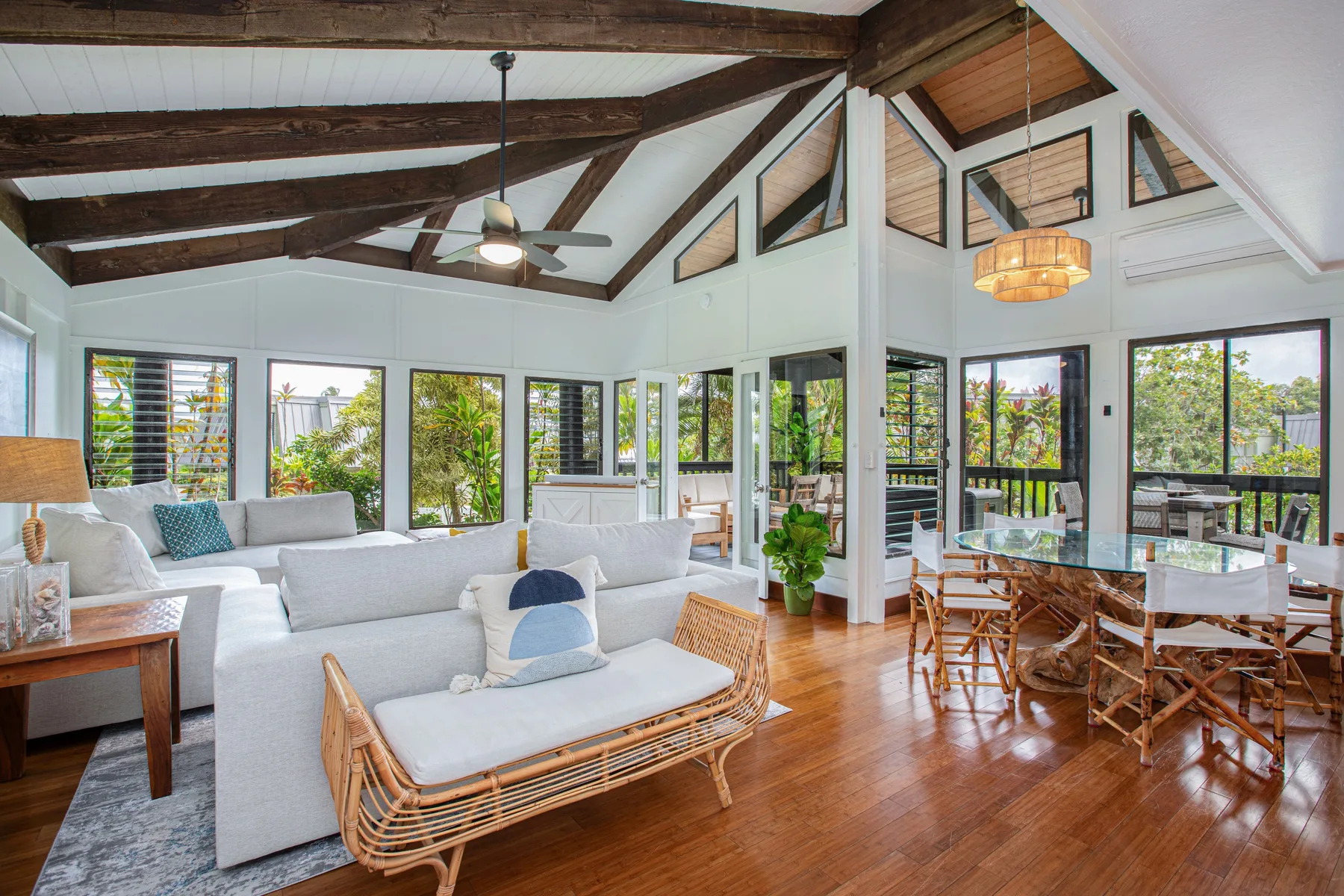 A bright living and dining area with seating, a dining table, and large windows.