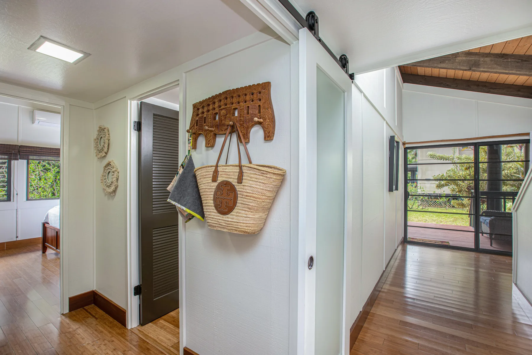A bright hallway opens onto rooms with large windows and wooden floors.