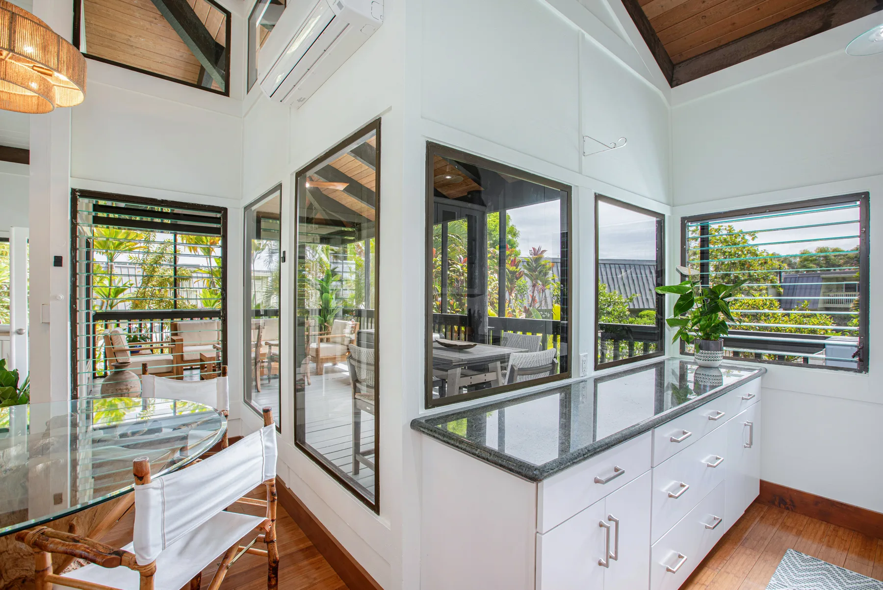 A bright kitchen with a central island and large windows overlooking greenery.