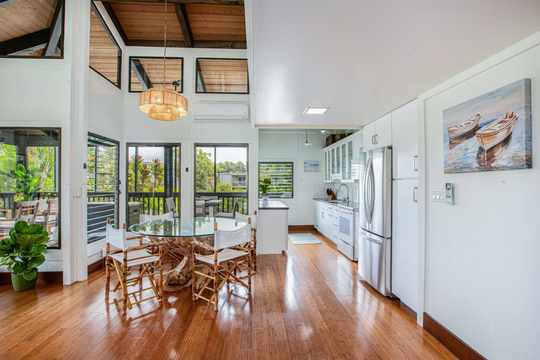 A bright open-plan kitchen and dining area with wooden flooring and large windows.