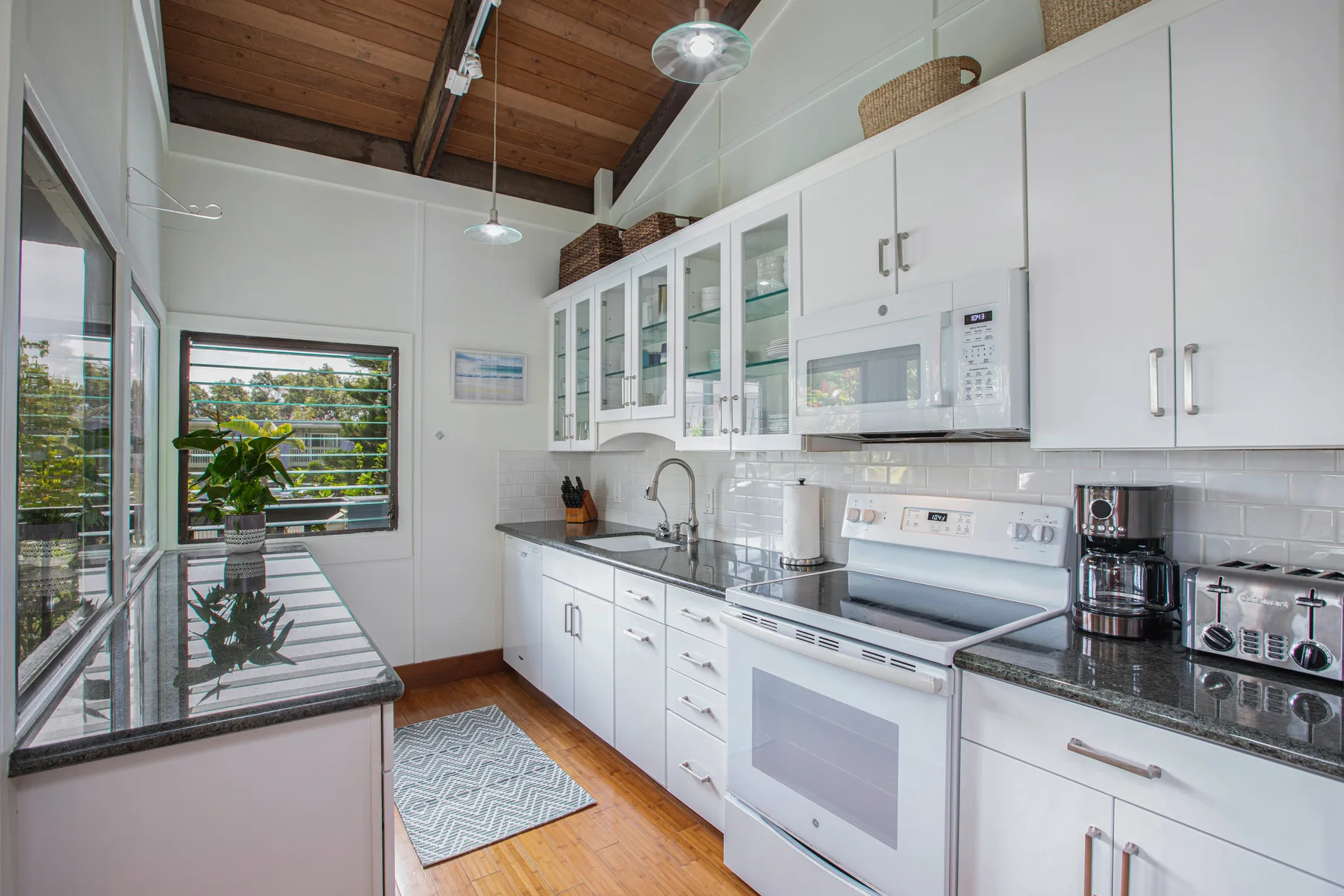 A bright kitchen with white cabinets, a countertop, and a large window.