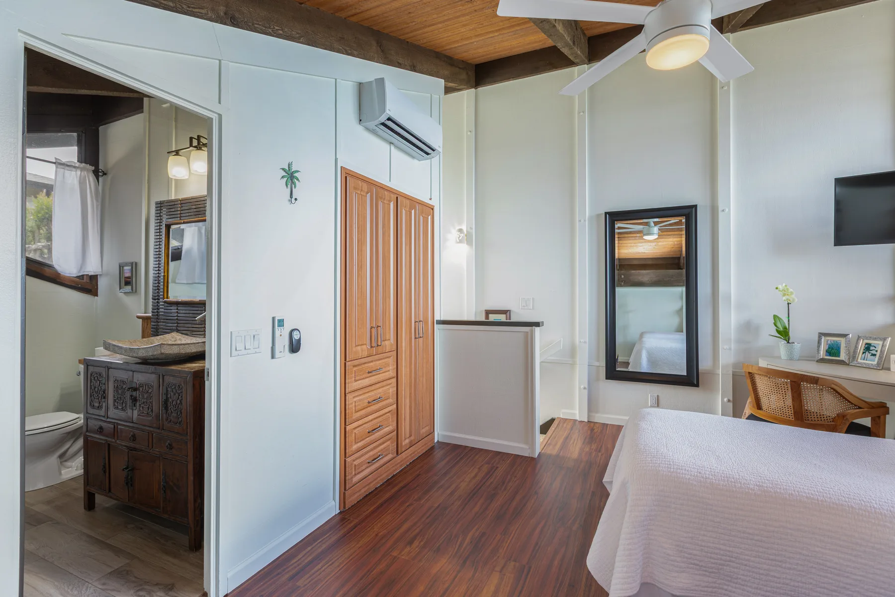 A bedroom with a bed, wooden wardrobe, and an open bathroom doorway.